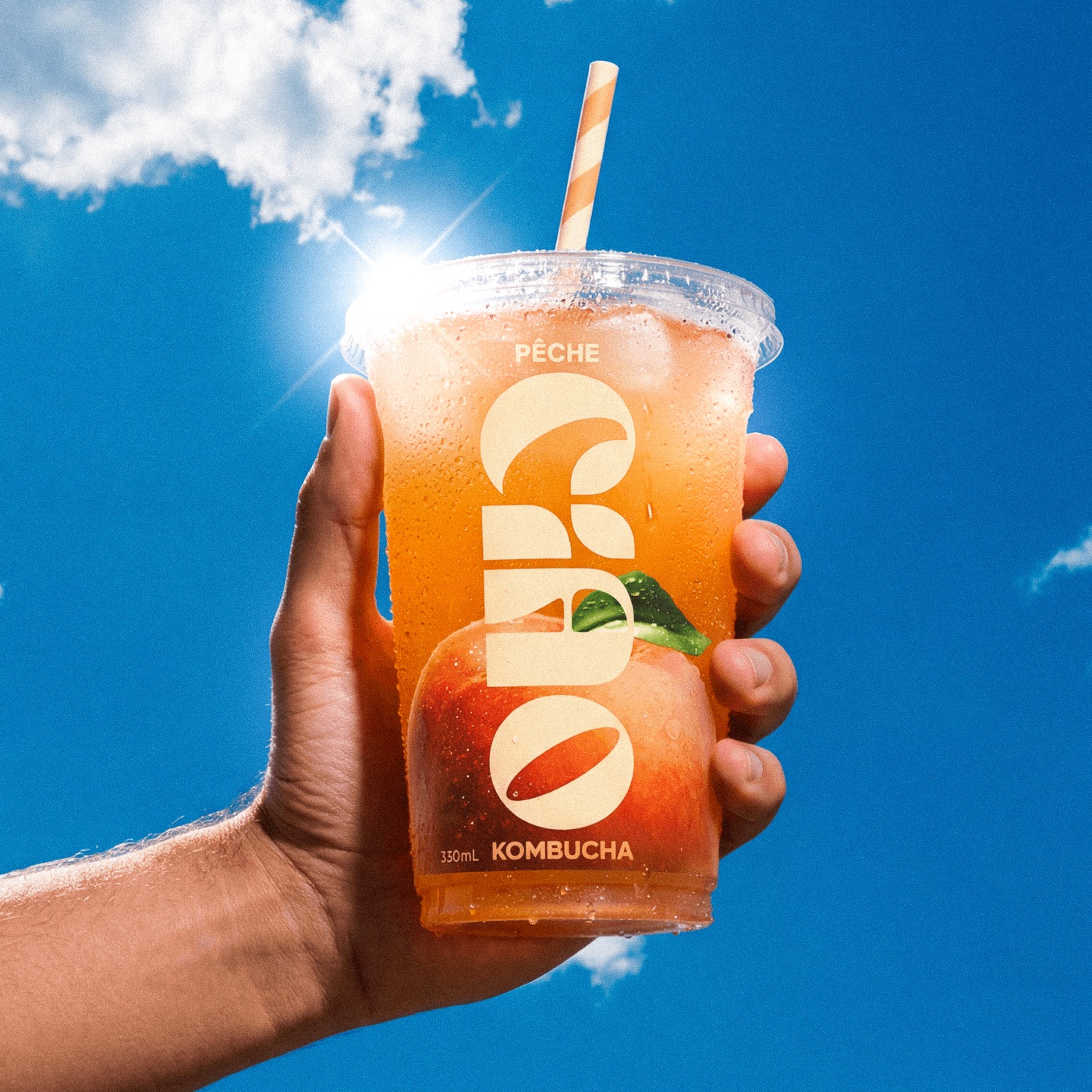 Ciao Kombucha — gobelet orange tenu devant ciel bleu