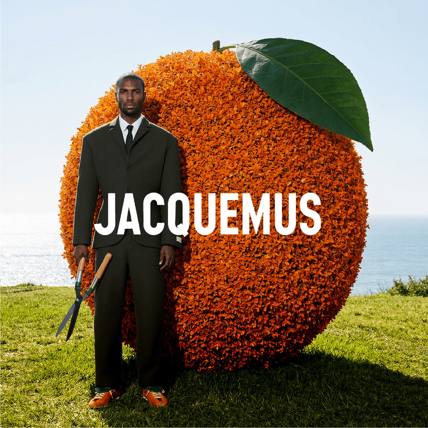Jacquemus — silhouette costume devant orange géante en paysage